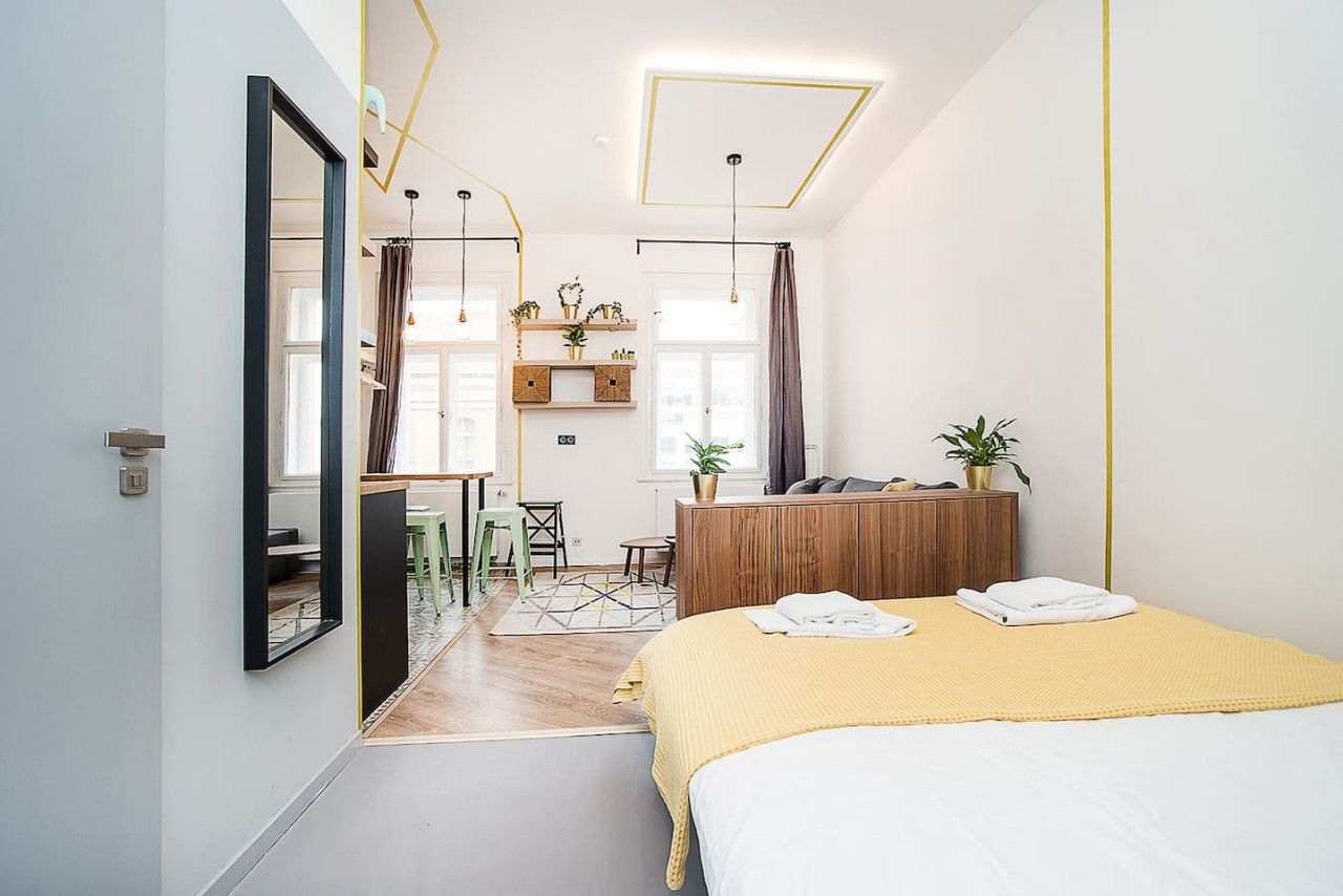 A modern bedroom with a bed, bedside tables, a desk, and a mirror.