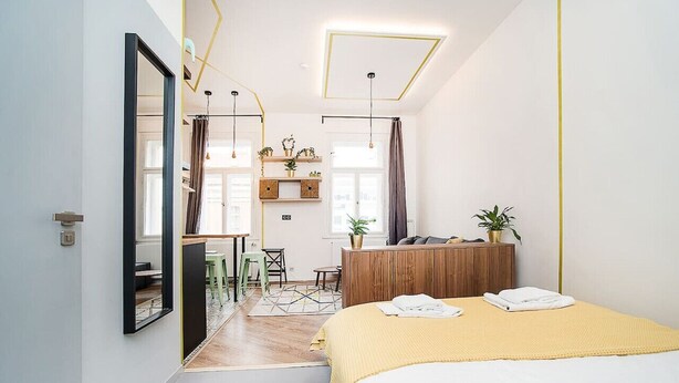 Ein modernes Schlafzimmer mit Bett, Nachttischen, einem Schreibtisch und einem Spiegel.