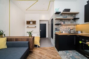 A compact living space with a kitchenette, a sofa, a bed, and a dining area.