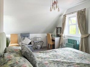 Une chambre à coucher comprenant un lit, un bureau, une chaise, une fenêtre avec des rideaux et un luminaire suspendu.
