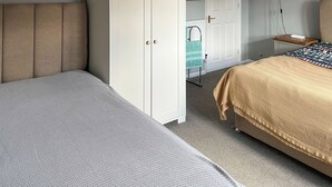 Ein Schlafzimmer mit Bett, Kleiderschrank, Nachttisch und Stehlampe.