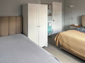 A bedroom with a bed, a wardrobe, a nightstand, and a floor lamp. - Beautiful tucked away property close to the town and beach. (Westgate-on-Sea)