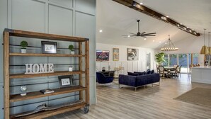 Un'ampia zona giorno con una libreria in legno, un divano blu e un tavolo da pranzo.