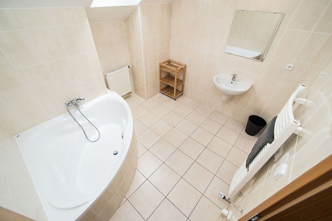 Une salle de bain avec une baignoire, un lavabo et une petite étagère en bois.