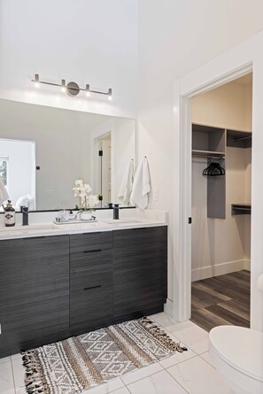 Une salle de bain moderne avec un meuble-lavabo en bois foncé, un grand miroir et un lavabo blanc.