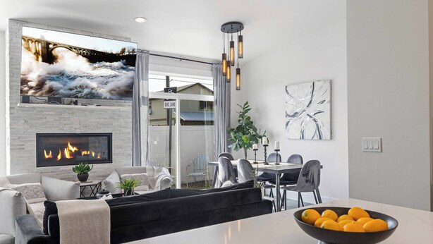 A modern living room with a fireplace, a dining area, and a view of a bridge and house. - New Modern Townhome- downtown CDA-minutes to waterfront, restaurants, and shops! (Coeur d'Alene)