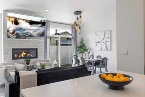 A modern living room with a fireplace, a dining area, and a view of a bridge and house. - New Modern Townhome- downtown CDA-minutes to waterfront, restaurants, and shops! (Coeur d'Alene)