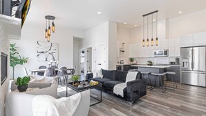 A modern living room with a sofa, coffee table, and a dining area. - New Modern Townhome- downtown CDA-minutes to waterfront, restaurants, and shops! (Coeur d'Alene)