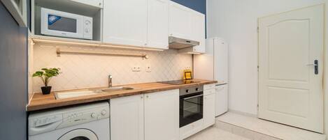 Een koelkast, een magnetron, een oven, kookgerei, borden en bestek