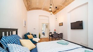 Une chambre à coucher avec un lit, des oreillers, un bureau et une télévision.