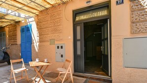 A building with a door, a scooter, and two chairs outside.