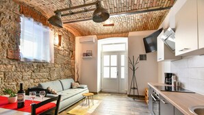 A cozy living area with a stone wall, a sofa, a dining table, and a kitchen with modern appliances.