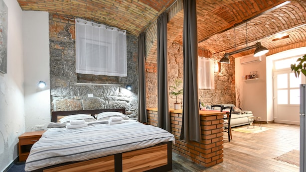 A bedroom with a wooden bed, stone wall, and a brick fireplace.
