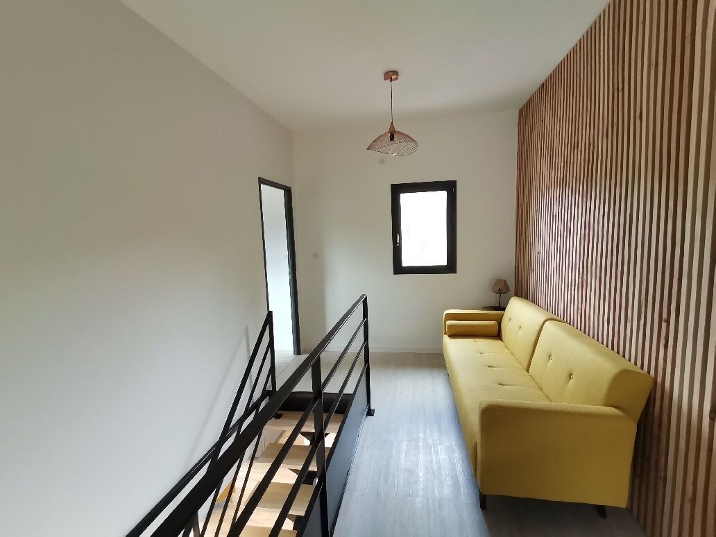 A modern interior with a yellow sofa, a staircase, and a striped wall.