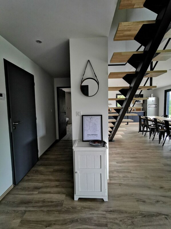 A modern interior with a staircase, a framed map, and a small cabinet.