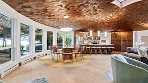 Una cocina moderna con una isla central, ventanas amplias y techo de madera.