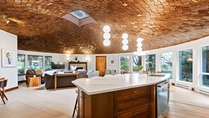 Una cocina amplia con una isla grande, techo de madera y ventanas grandes.