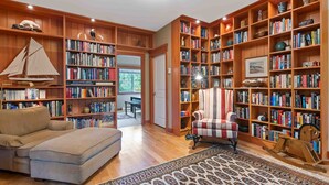 A cozy reading nook with a large bookshelf, a plush sofa, and a rocking chair. - Coastal Haven-N Chesterman Beach, Hot Tub, Surf! (Tofino)