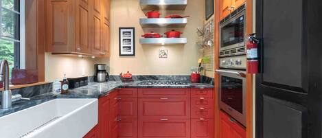 Una cocina moderna con armarios rojos, un lavamanos de acero inoxidable y un horno empotrado.