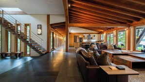 A spacious interior with a staircase, a living area with a sofa and coffee table, and a kitchen area. - Coastal View-Rated top place to stay on the inlet! (Tofino)