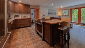 A modern kitchen with wooden cabinets, a central island, and a dining area with a sofa and chairs.