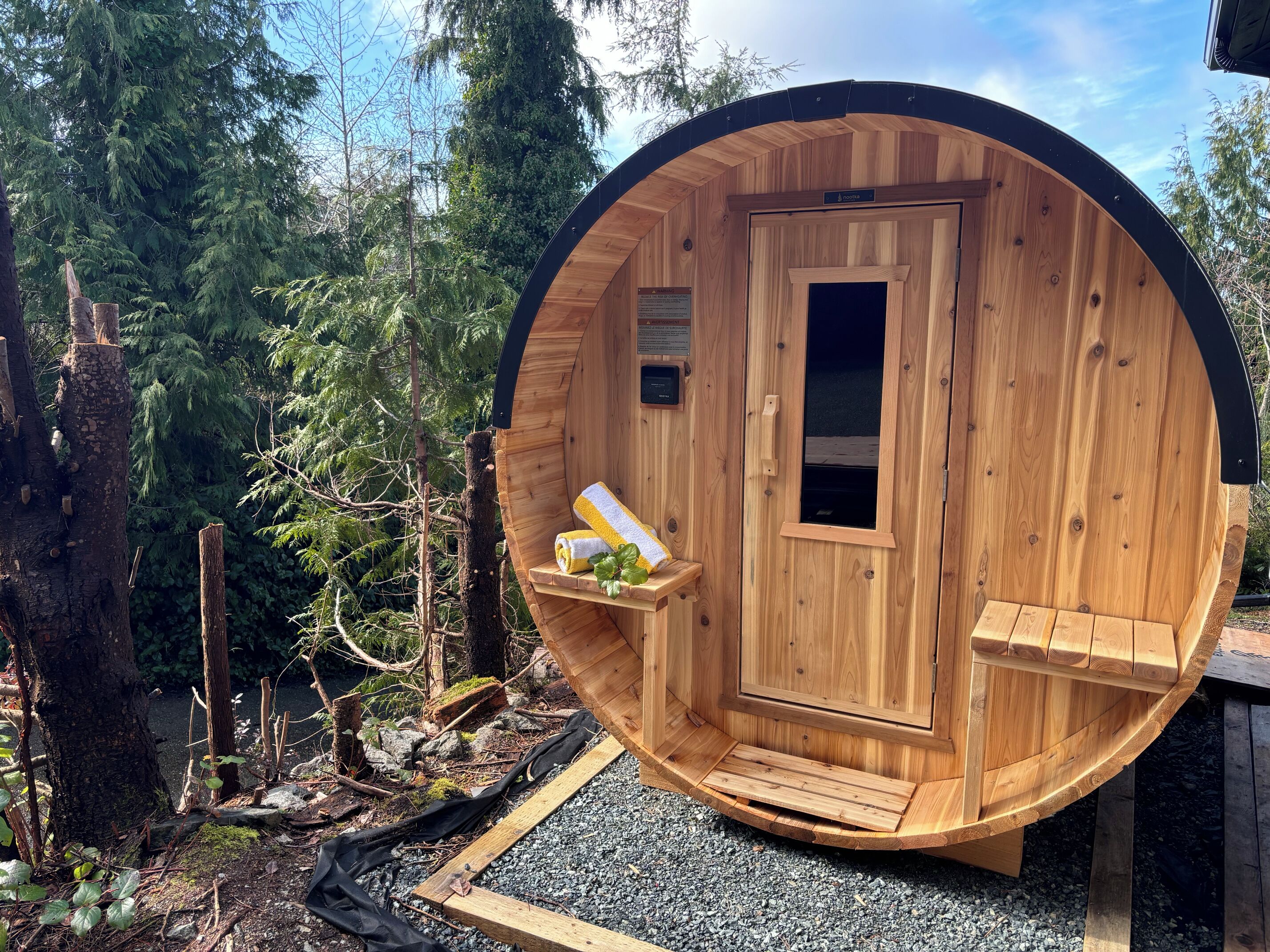 A wooden sauna with a door, a window, and a towel rack.