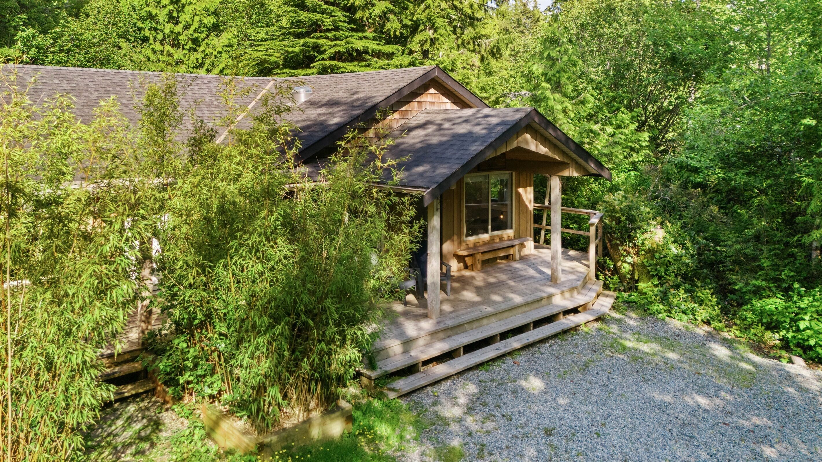 A cabin with a porch, surrounded by dense forest.
