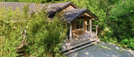 A cabin with a porch, surrounded by dense forest.