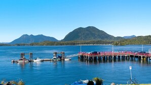 A pier extending into a lake with boats docked, surrounded by mountains and dense forest. - Fred Tibbs #10-Ocean View, D.T, Fireplace, Pets (Tofino)