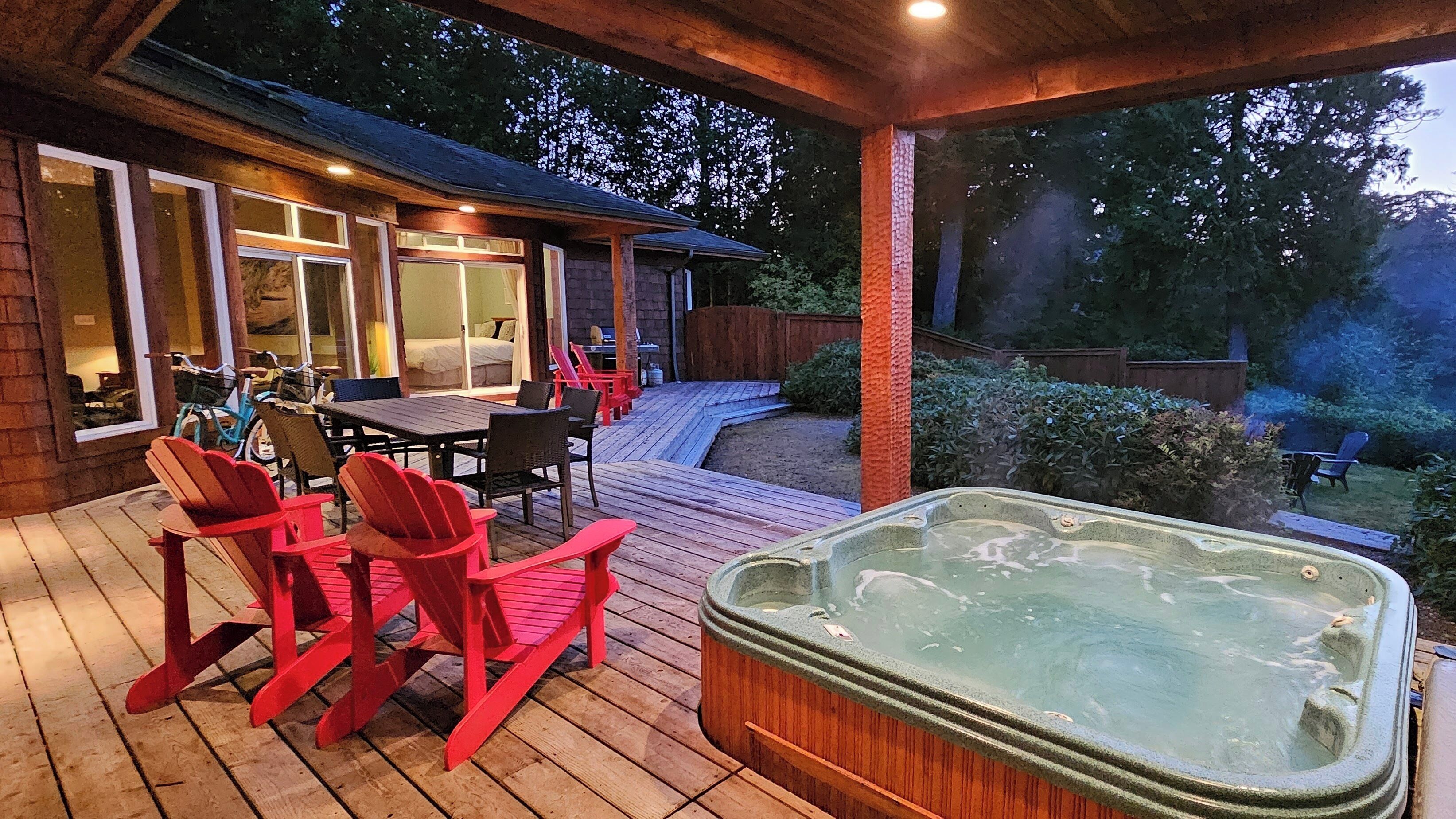 Eine Holzterrasse mit Gartenmöbeln, einem Whirlpool und einer Terrasse mit Blick auf den Garten.