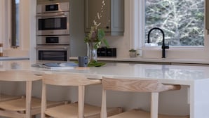 A modern kitchen with wooden cabinets, a built-in oven, and a large window.