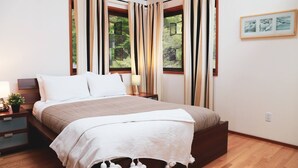 Une chambre à coucher avec un lit, des tables de chevet, une lampe et une fenêtre avec des rideaux.