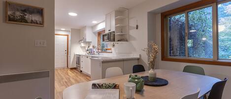 A modern kitchen with white cabinets, a central island, and a dining area with a round table and chairs.