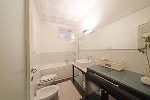 A modern bathroom with a bathtub, toilet, and sink. - Downtown Apartment (Salò)