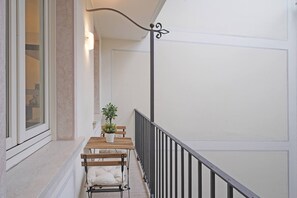 A balcony with a wooden table and two benches, a potted plant, and a black metal railing. - Downtown Apartment (Salò)