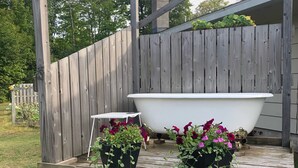 Eine Holzterrasse mit einer weißen Badewanne und Topfpflanzen.