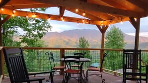 A wooden deck with a table and chairs, overlooking a mountainous landscape. - Spectacular Smoky Mtn. Views from Oversized Hot Tub Close to Downtown Gatlinburg (Gatlinburg)