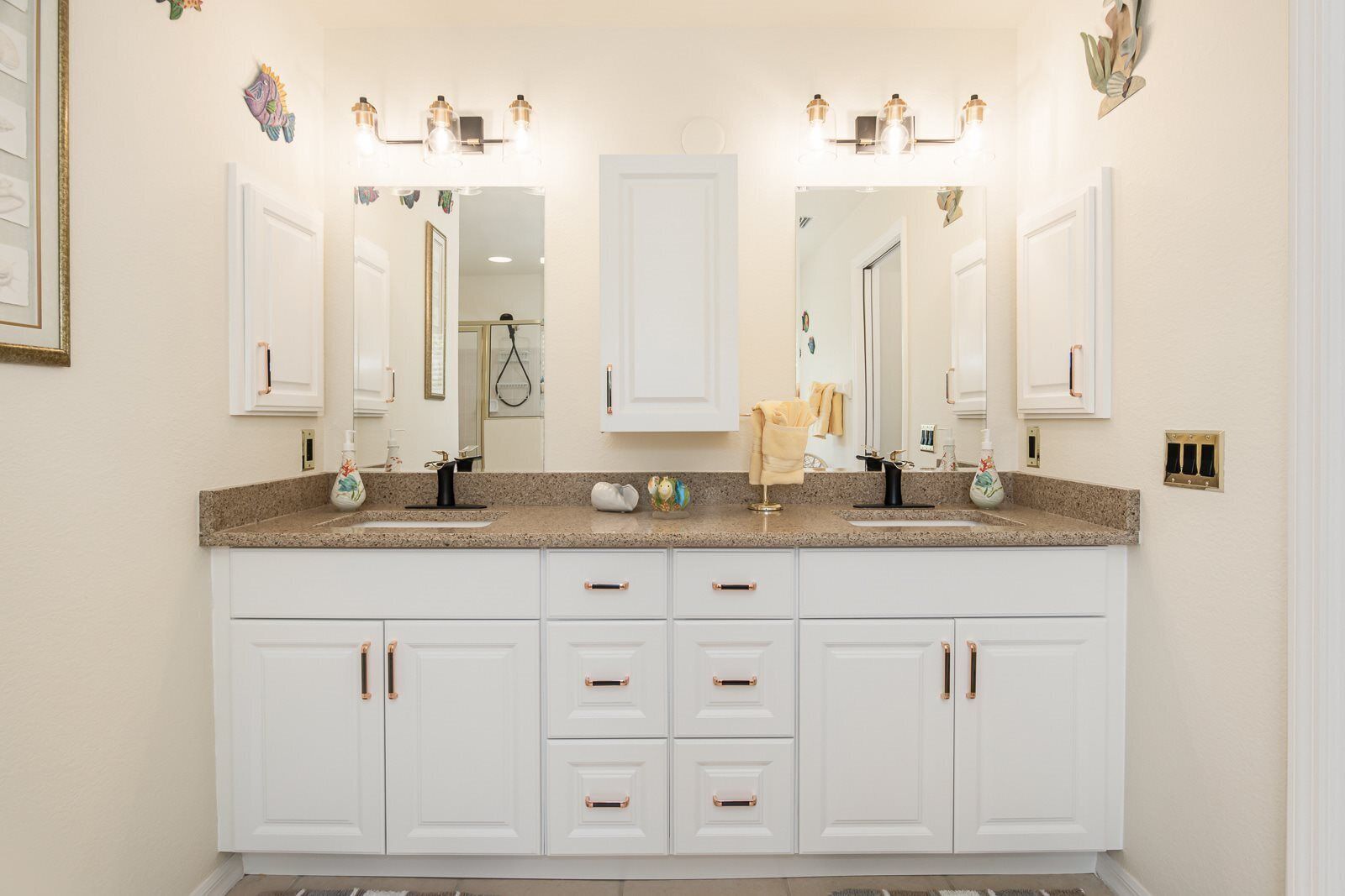 A bathroom with a double vanity, two sinks, a large mirror, and a lighted vanity area.