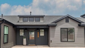 A two-story house with a dark gray exterior, a front porch, and a large potted plant. - BLACK SHEEP INN Newly Constructed Suffolk #2 of 4 Units  (Cedar City)