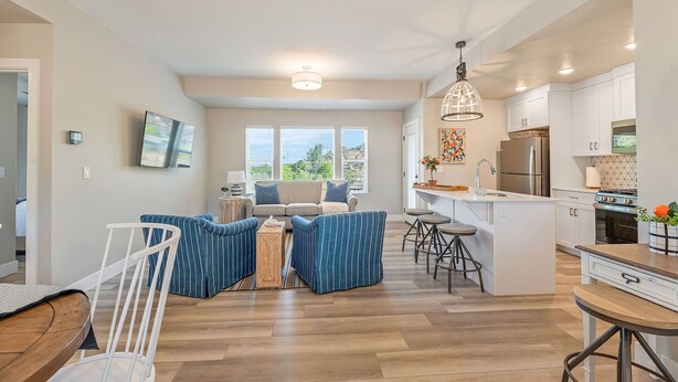 A modern kitchen with white cabinetry, a central island, and bar stools. - BLACK SHEEP INN Newly Constructed Suffolk #2 of 4 Units  (Cedar City)