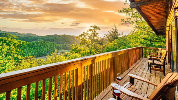 A wooden deck with outdoor seating and a scenic view of a forested valley. - 🏔Sunset Mtn views!⛰ 5 min to PFORGE🚙  HOT TUB! ♨️ (Pigeon Forge)