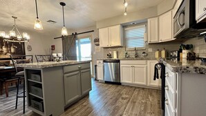 A modern kitchen with a central island, white cabinetry, and a stainless steel dishwasher.