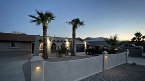A residential area with a house featuring a garage, a driveway, and a well-lit entrance.
