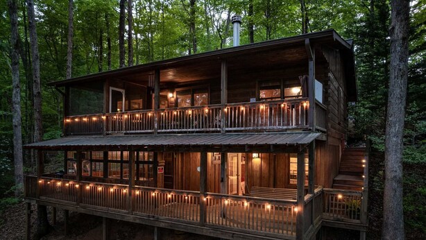 A two-story wooden cabin with a balcony, surrounded by trees. - Sunrise View-10 Min to Blue Ridge,Hot Tub-3 BR (Blue Ridge)