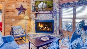 A cozy cabin interior with a stone fireplace, a mounted TV, and a comfortable seating area. - Sunrise View-10 Min to Blue Ridge,Hot Tub-3 BR (Blue Ridge)