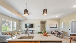 Une cuisine moderne dotée d’un îlot central, de deux suspensions et d’un coin repas avec une table et des chaises.