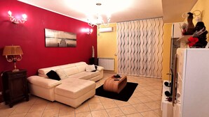 Una sala de estar con pared roja, sofá color beige, mesita de madera y alfombra negra.