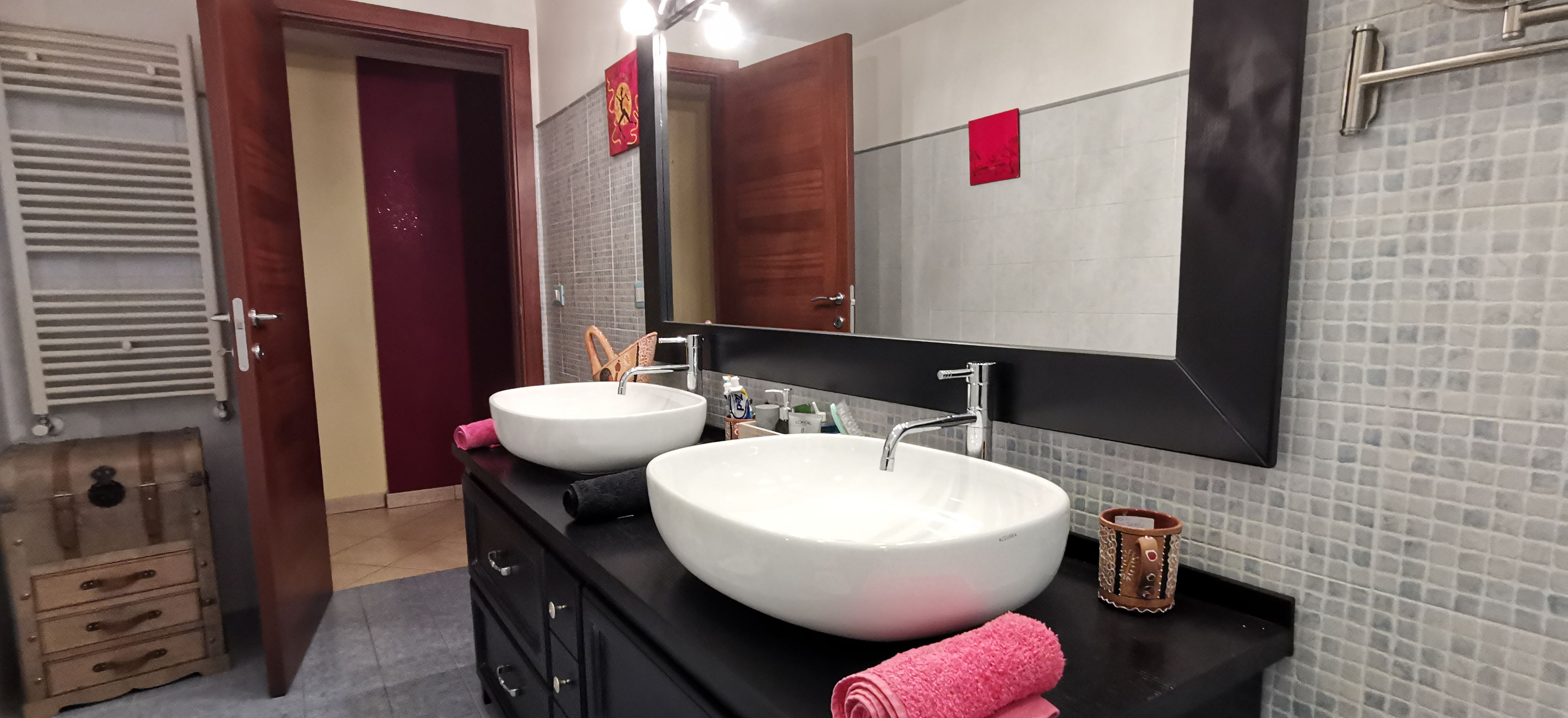 A bathroom with two large white sinks, a mirror, and a wooden cabinet.