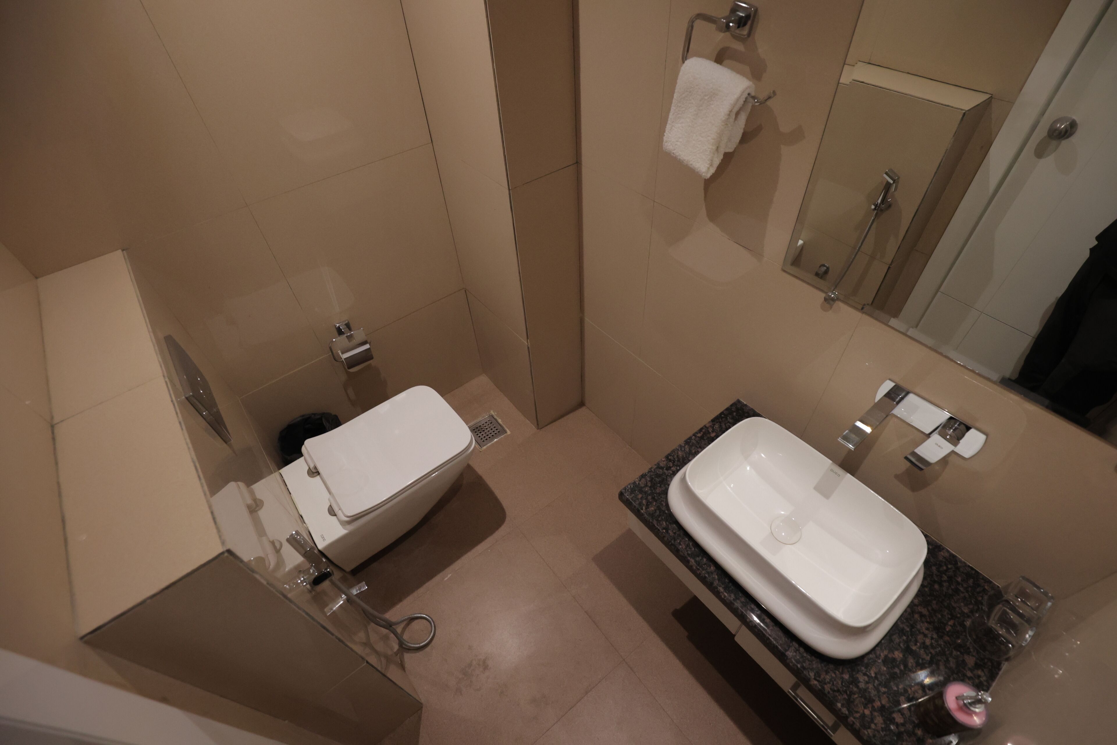 Een moderne badkamer met toilet, wastafel en spiegel.