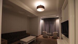Una sala de estar moderna con un sofá, una mesa de centro y dos sillones. Un televisor de pantalla plana está montado en la pared.